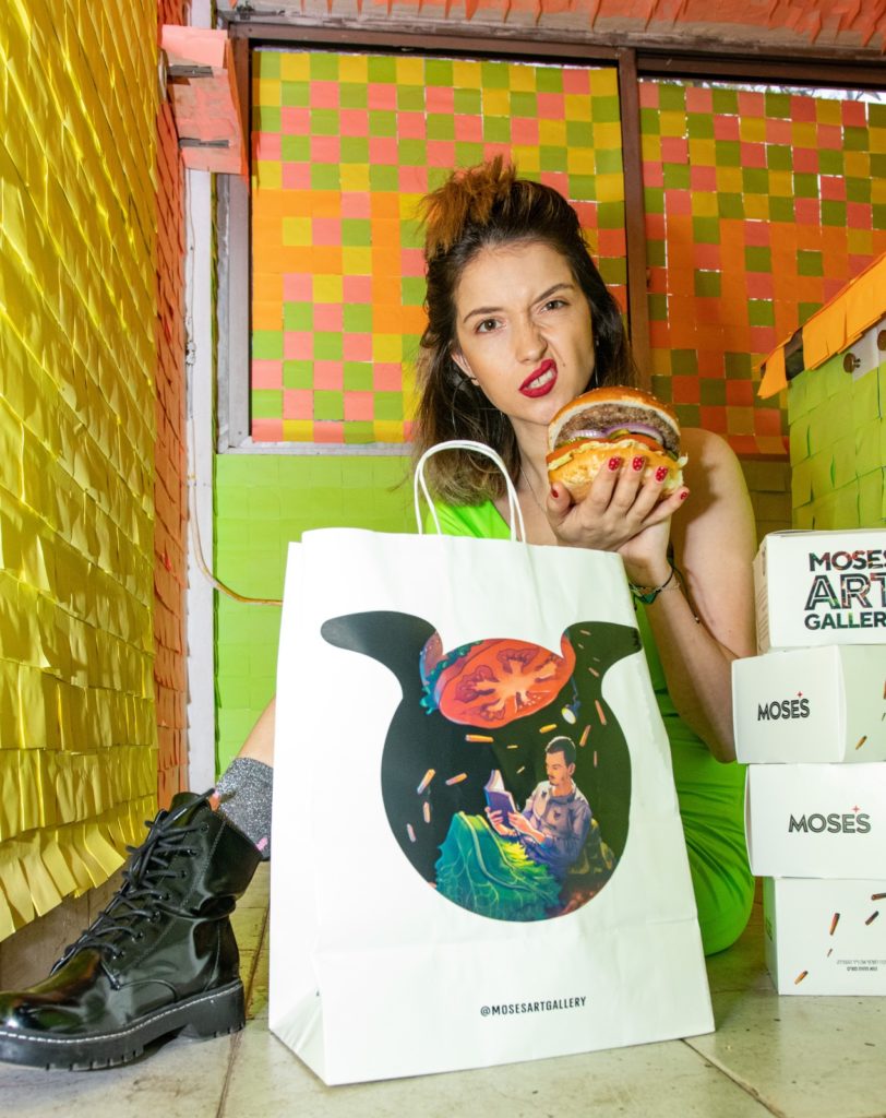 תמונת אווירה בחורה מחזיקה המבורגר ליד קופסאות משלוח